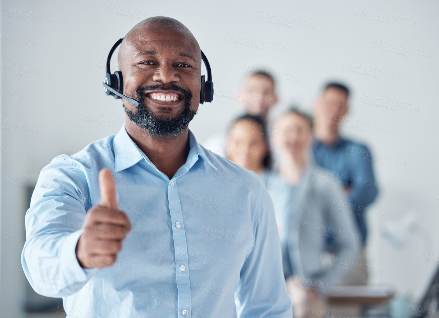 Buy stock photo Portrait of a mature call centre agent showing thumbs up in an office with his colleagues in the background