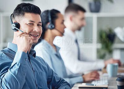 Buy stock photo Portrait of a young call centre agent working in an office with his colleagues in the background