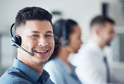 Buy stock photo Portrait of a young call centre agent working in an office with his colleagues in the background