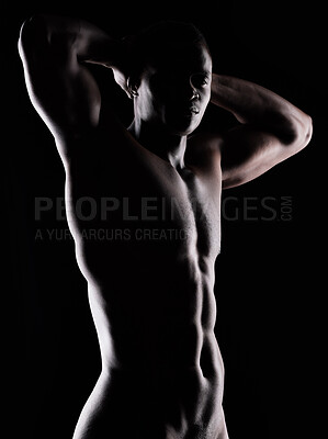 Buy stock photo Artistic shot of a muscular young man posing in studio against a dark background