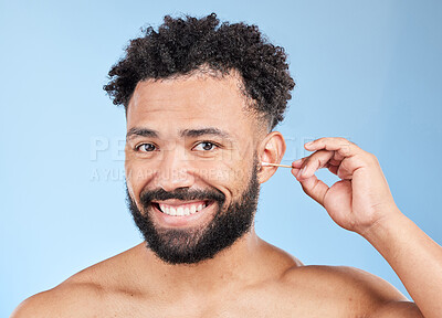 Buy stock photo Portrait, man and cotton for cleaning ear with hygiene, wellness and morning grooming in studio. Male person, smile and cosmetics product for earwax removal, health and happy by blue background