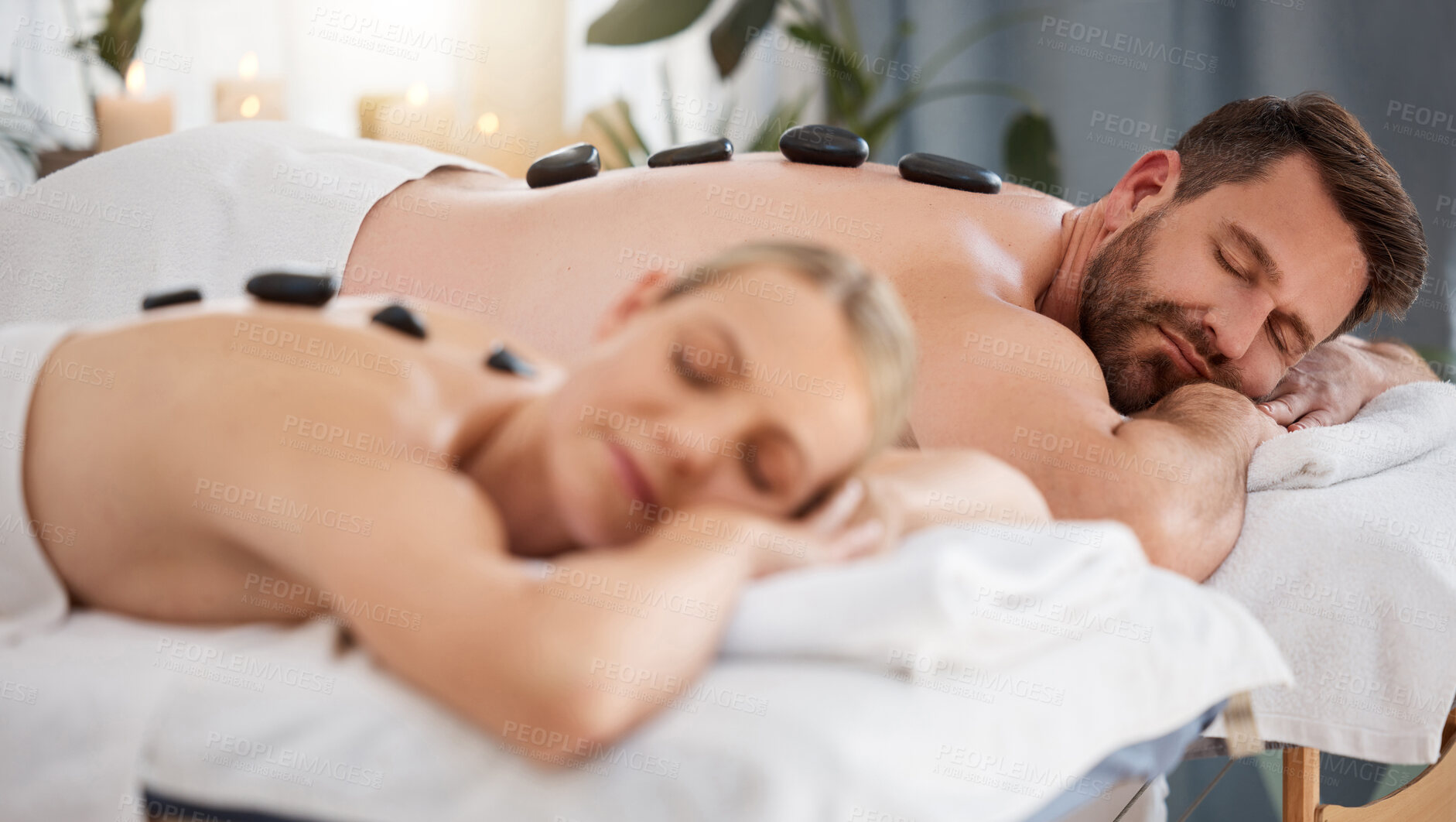 Buy stock photo Couple, relax and stone massage for wellness, body pain and zen vacation in spa. Man, woman and hot rock treatment in luxury salon for healing muscle, holistic therapy and calm holiday in Thailand