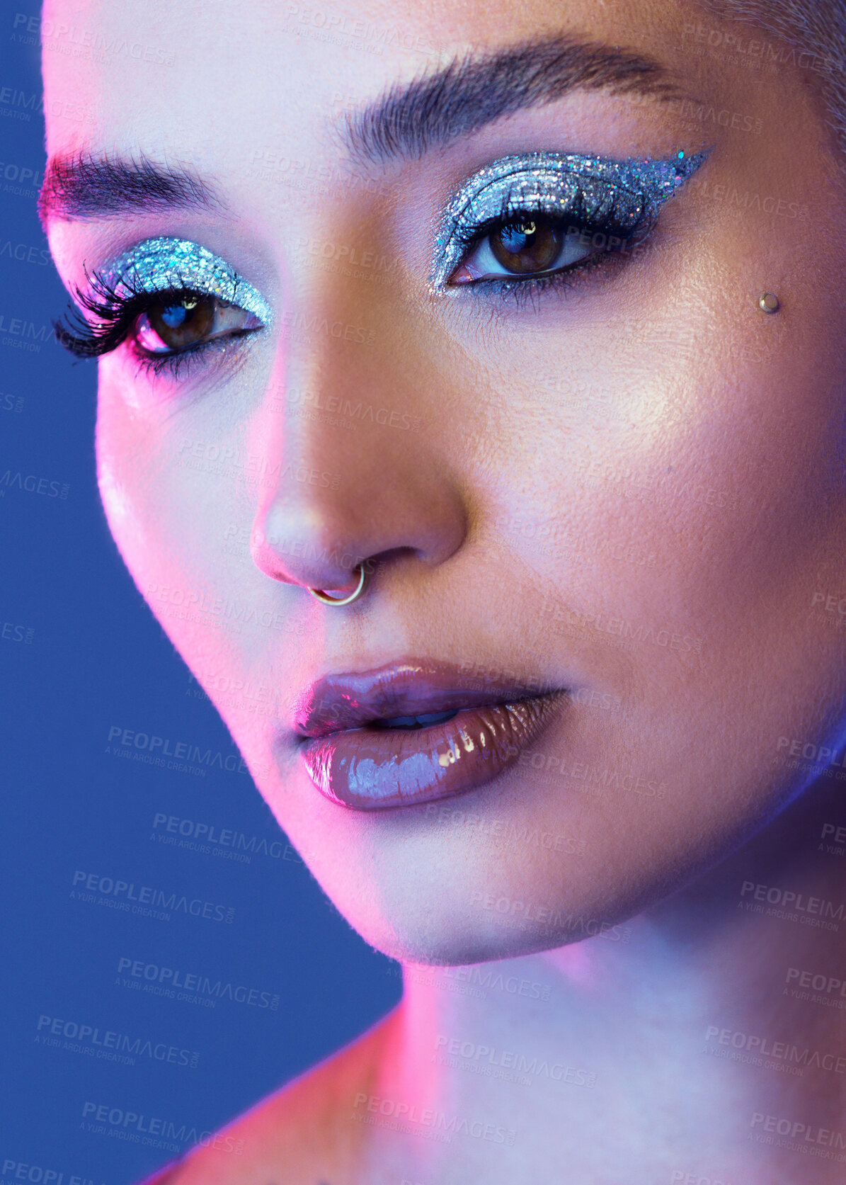 Buy stock photo Studio shot of an attractive young woman wearing edgy makeup against a blue background