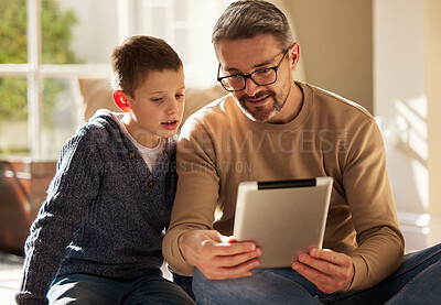Buy stock photo Shot of a father and son using a digital tablet together at home