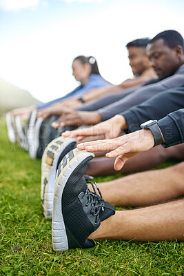 Buy stock photo Closeup shot of a group of unrecognisable people stretching their legs while exercising together outdoors