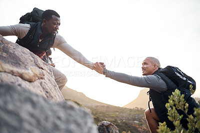 Buy stock photo Cropped shot of a handsome young man helping his friend along a mountain during their hike