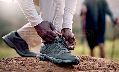 Buy stock photo Cropped shot of an unrecognizable man tying his laces while hiking in the mountains with his friend