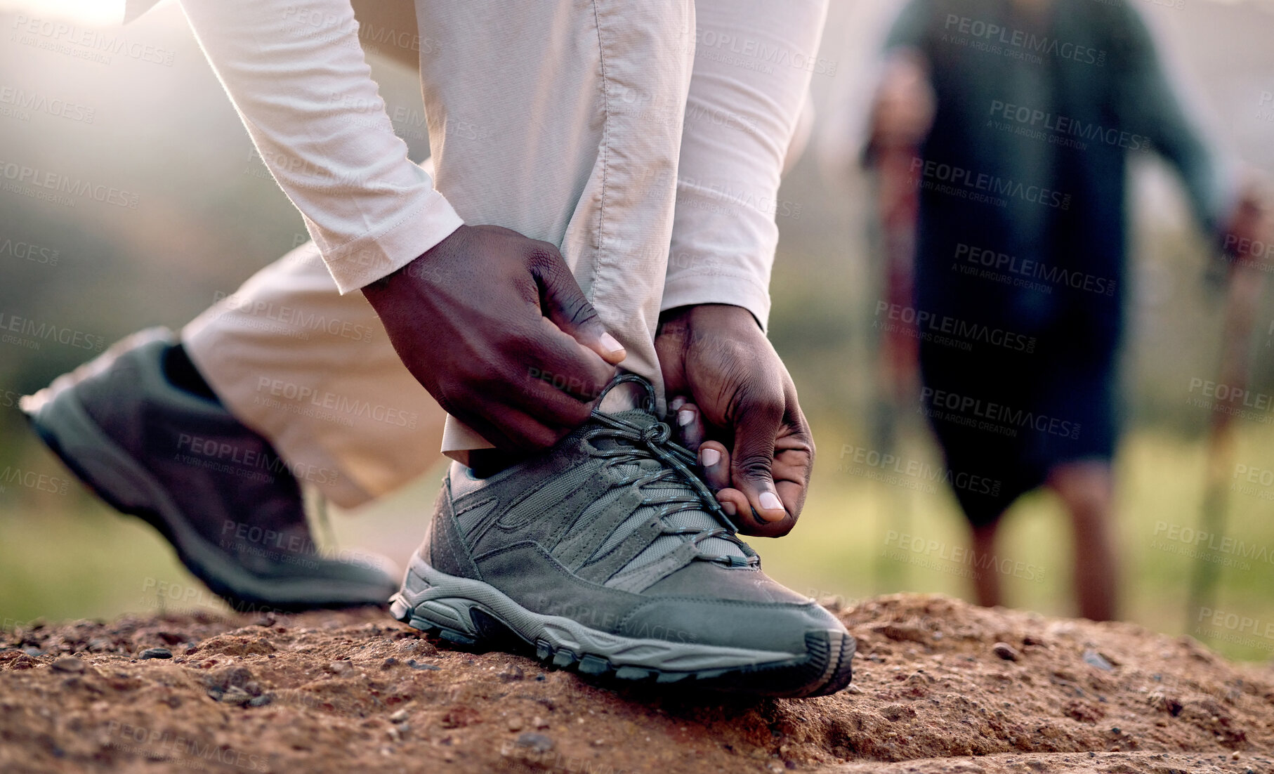 Buy stock photo Cropped shot of an unrecognizable man tying his laces while hiking in the mountains with his friend