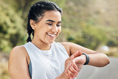 Buy stock photo Shot of a young woman checking her watch while out for a run