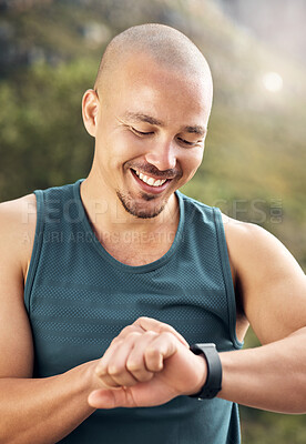 Buy stock photo Shot of a young man checking his watch while out for a run