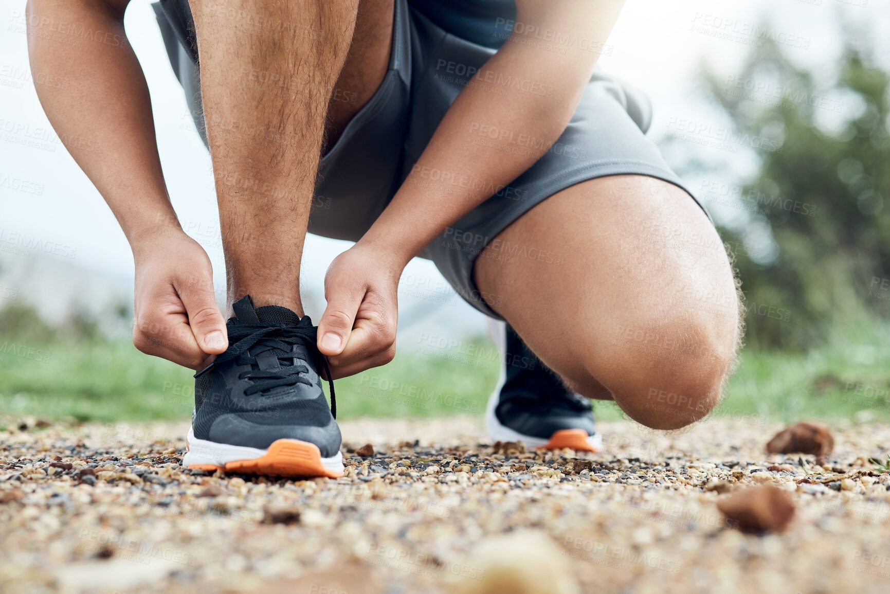 Buy stock photo Shot of an athletic man tying his laces while our for a run