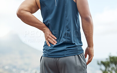 Buy stock photo Shot of a sporty young man experiencing back pain while out for a run