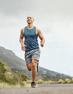Buy stock photo Shot of an athletic young man out for a run on a mountain road