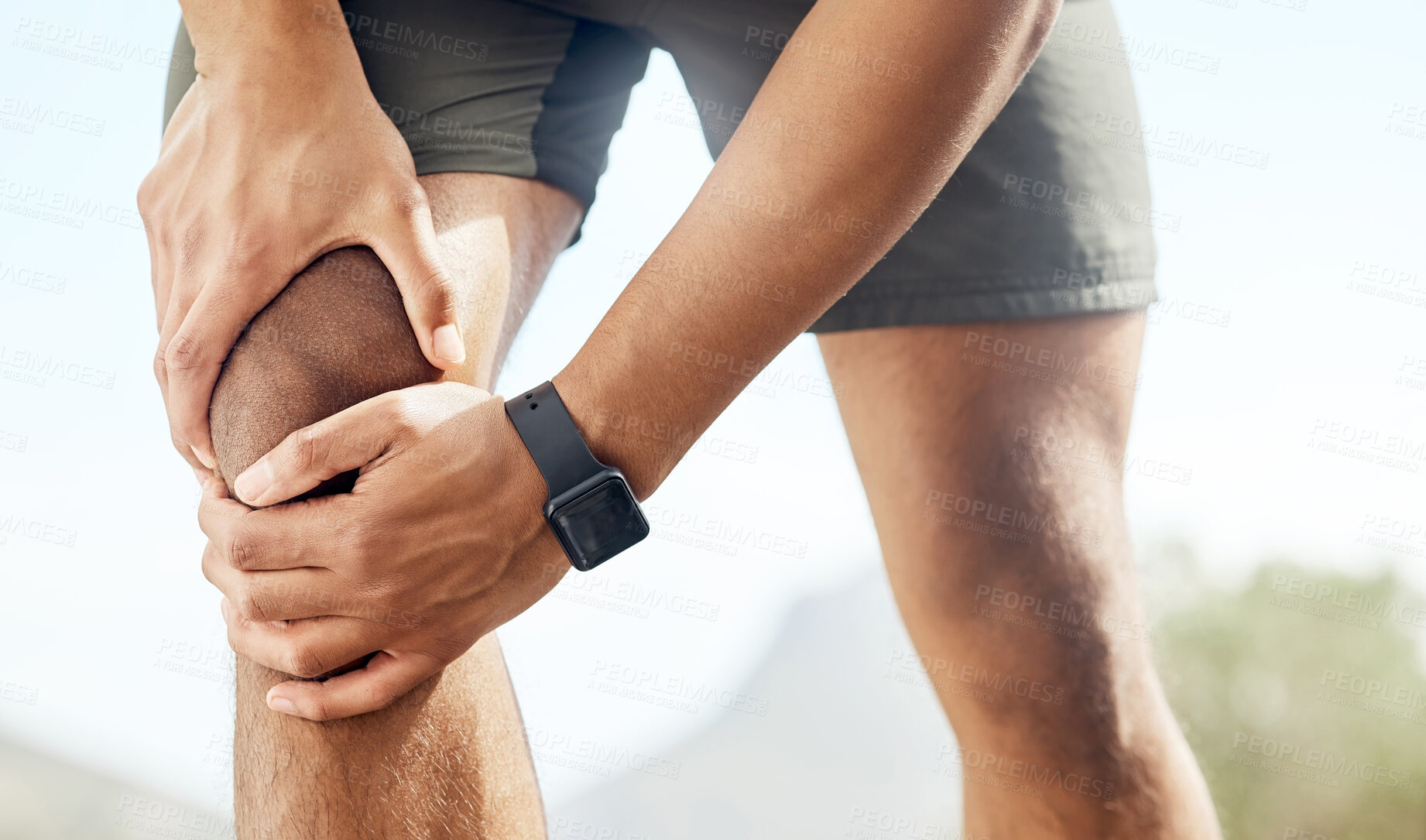 Buy stock photo Shot of a sporty young man experiencing discomfort in his knee while out for a run