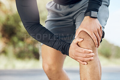 Buy stock photo Shot of a sporty young man experiencing discomfort in his knee while out for a run