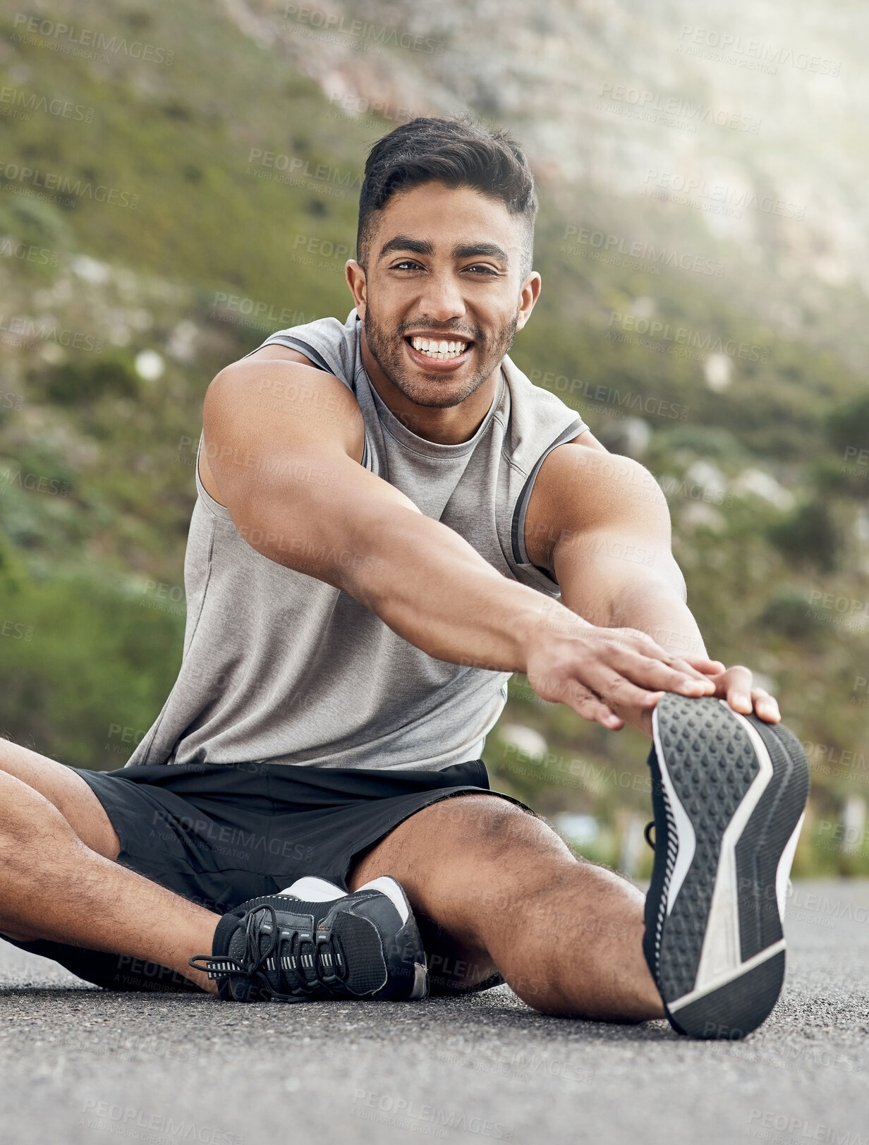 Buy stock photo Shot of an athletic young man stretching on a mountain road
