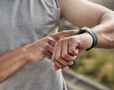 Buy stock photo Cropped shot of a man checking his watch while out for a run