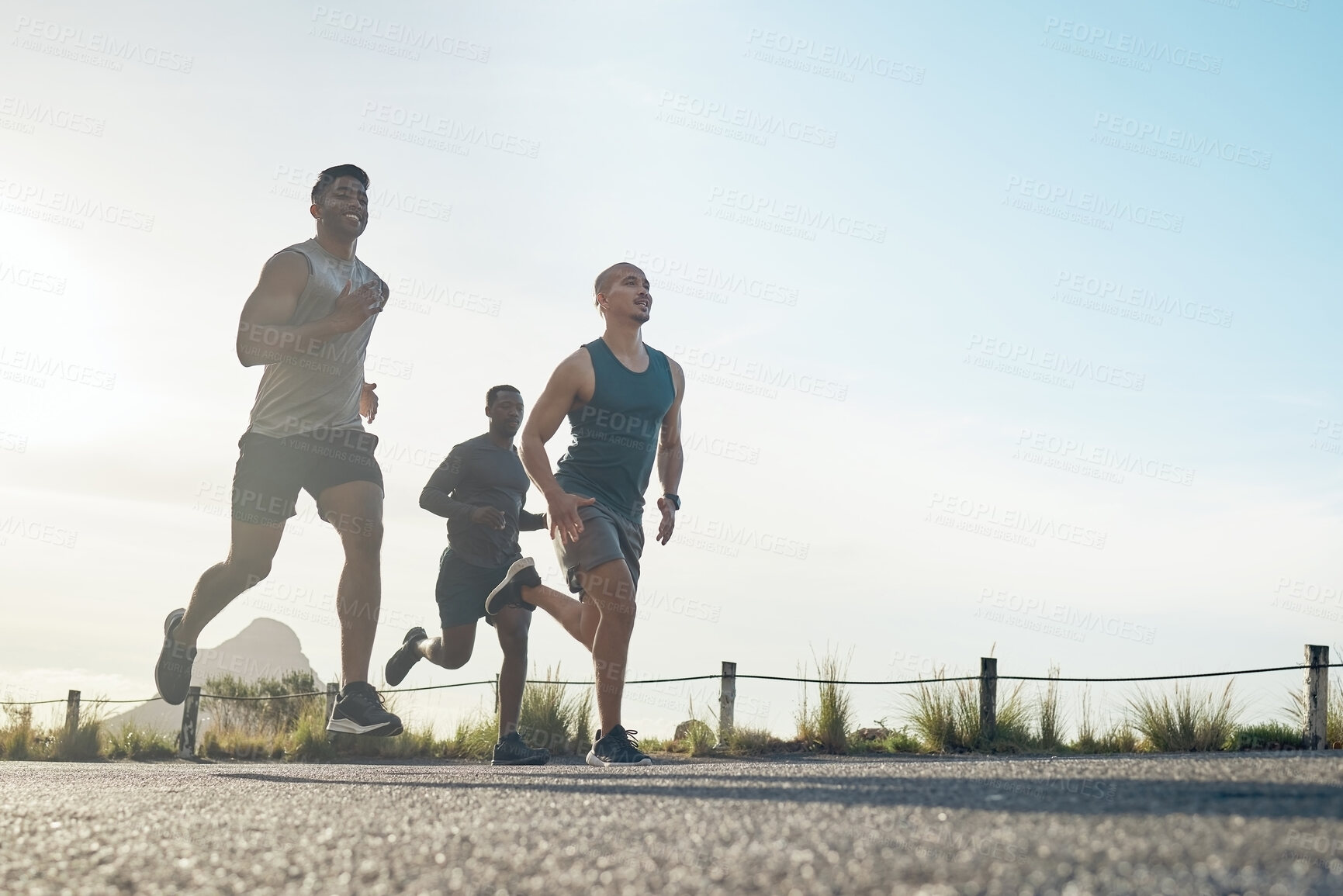 Buy stock photo Shot of three athletic young men out for a run together