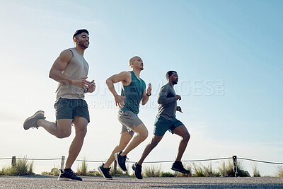 Buy stock photo Shot of three athletic young men out for a run together