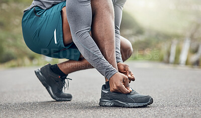 Buy stock photo Shot of an athletic man tying his laces while our for a run