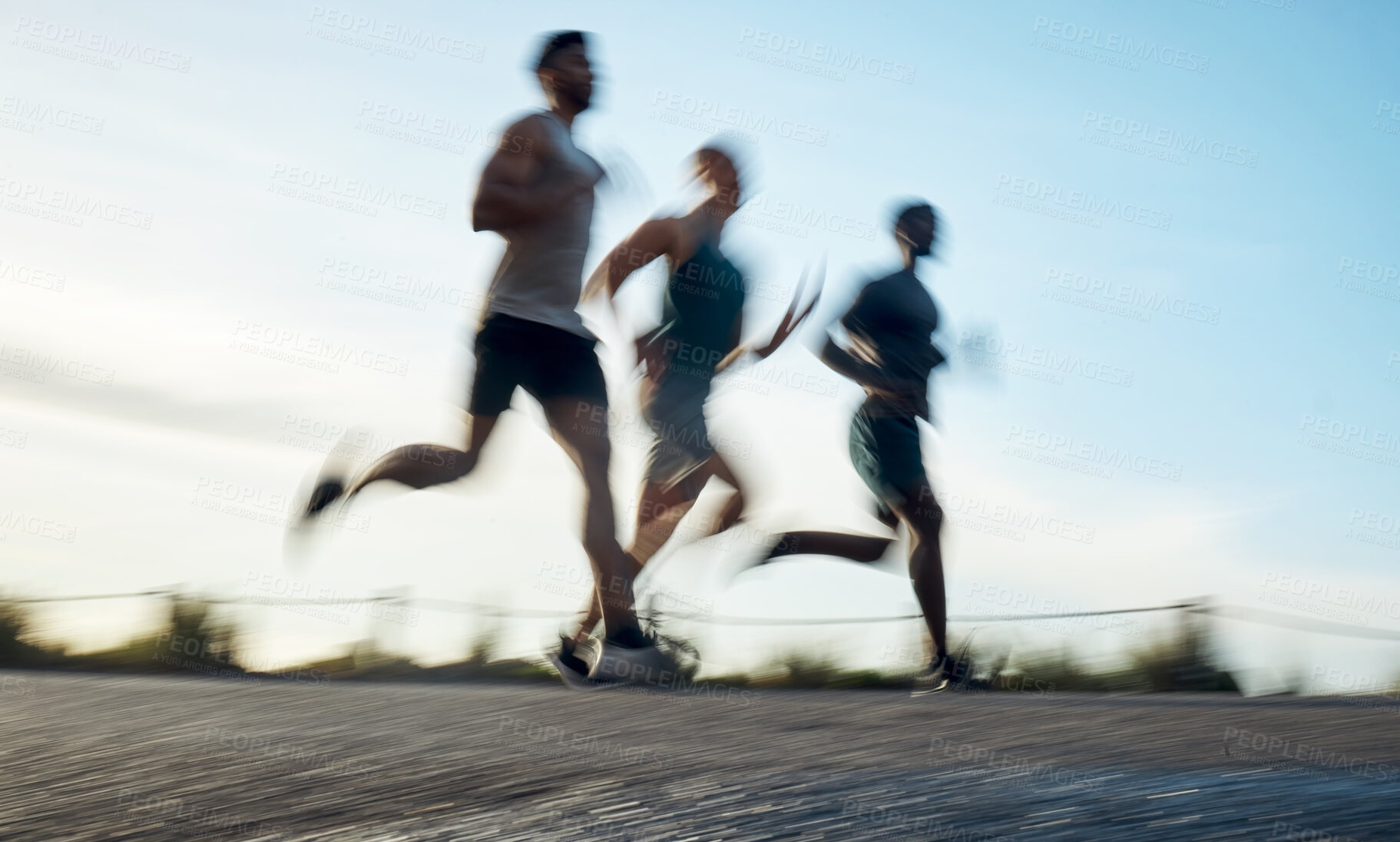 Buy stock photo Blurred shot of three athletic young men running together