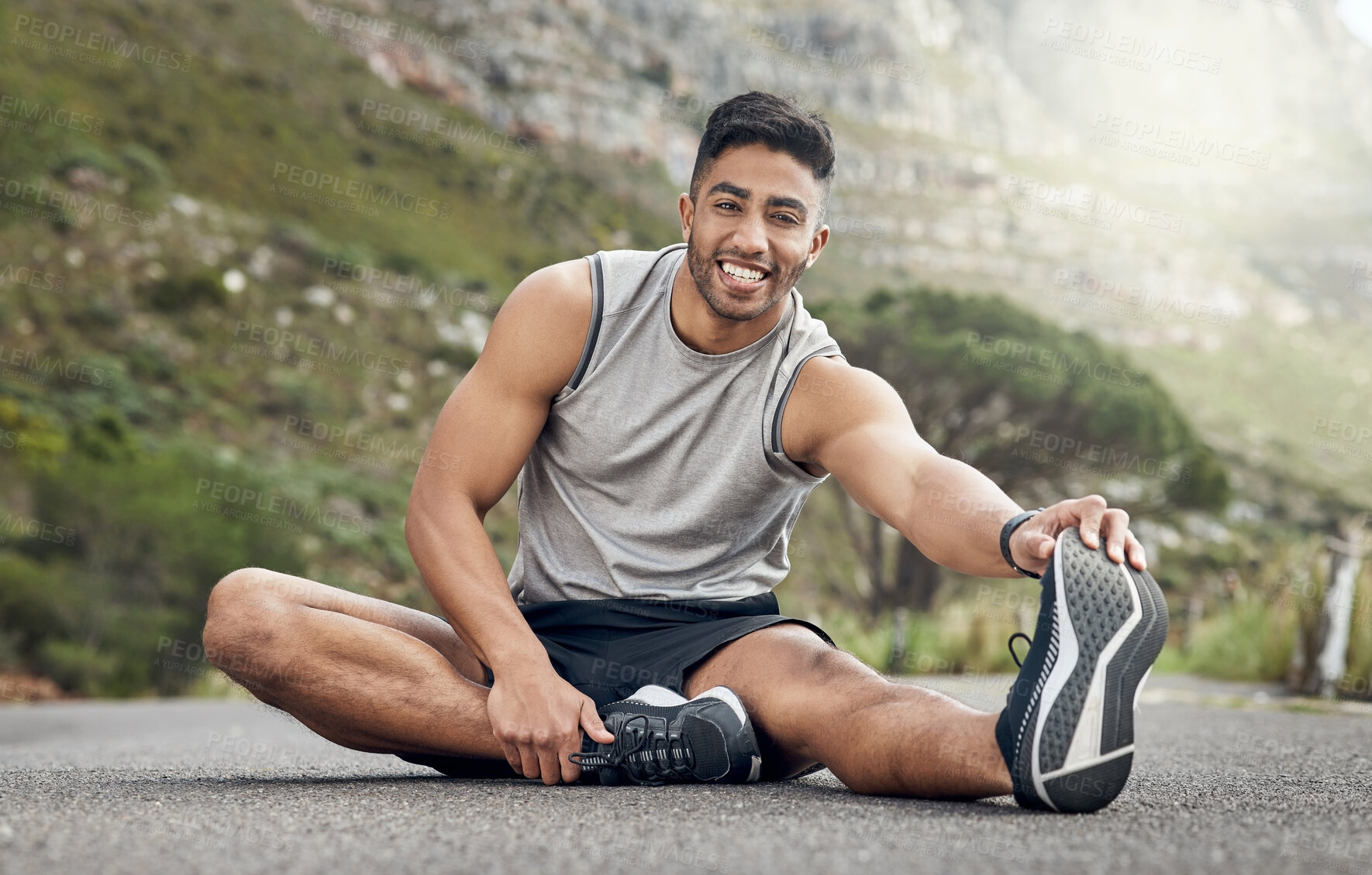 Buy stock photo Shot of an athletic young man stretching on a mountain road