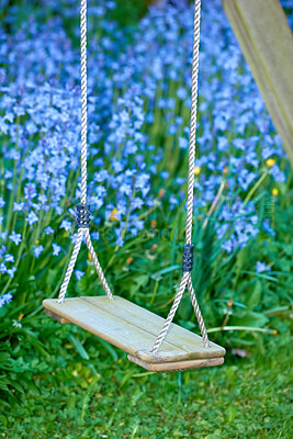 Buy stock photo Old wooden swing in a garden with blue flowers and moss in a lush backyard. Peaceful scene of a forgotten playground with vibrant wild bluebells and overgrown lawn in spring with copy space