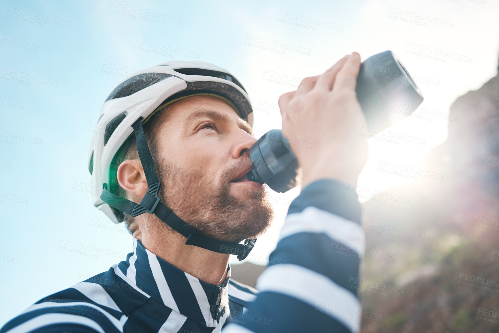 Buy stock photo Cropped shot of a handsome mature man taking a water break while cycling outdoors