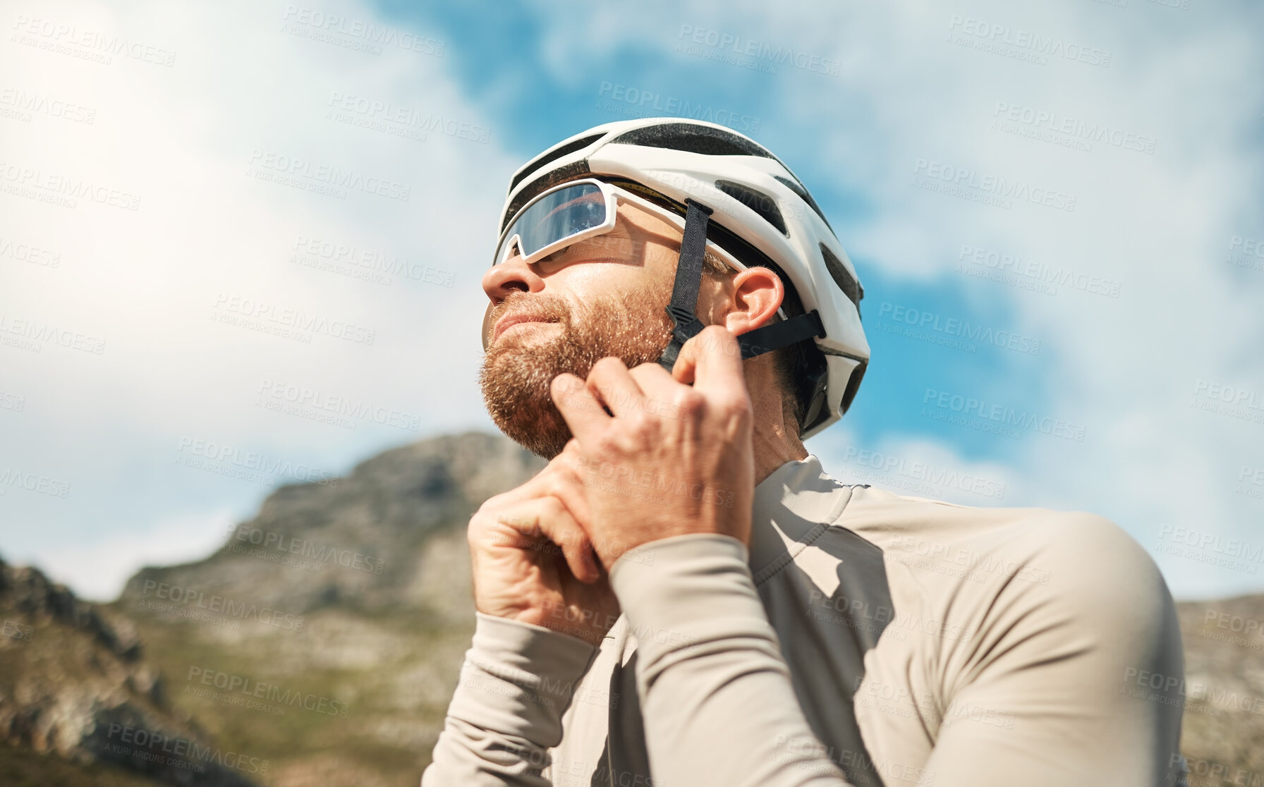 Buy stock photo Cropped shot of a handsome mature man fastening his helmet while cycling outdoors