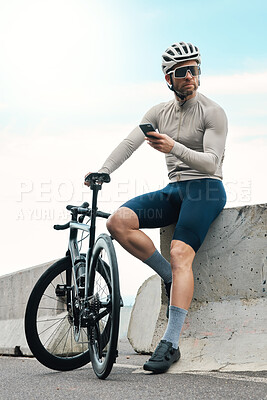 Buy stock photo Full length shot of a handsome mature man taking a break to check his phone while cycling outdoors