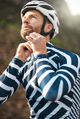 Buy stock photo Cropped shot of a handsome mature man fastening his helmet while cycling outdoors