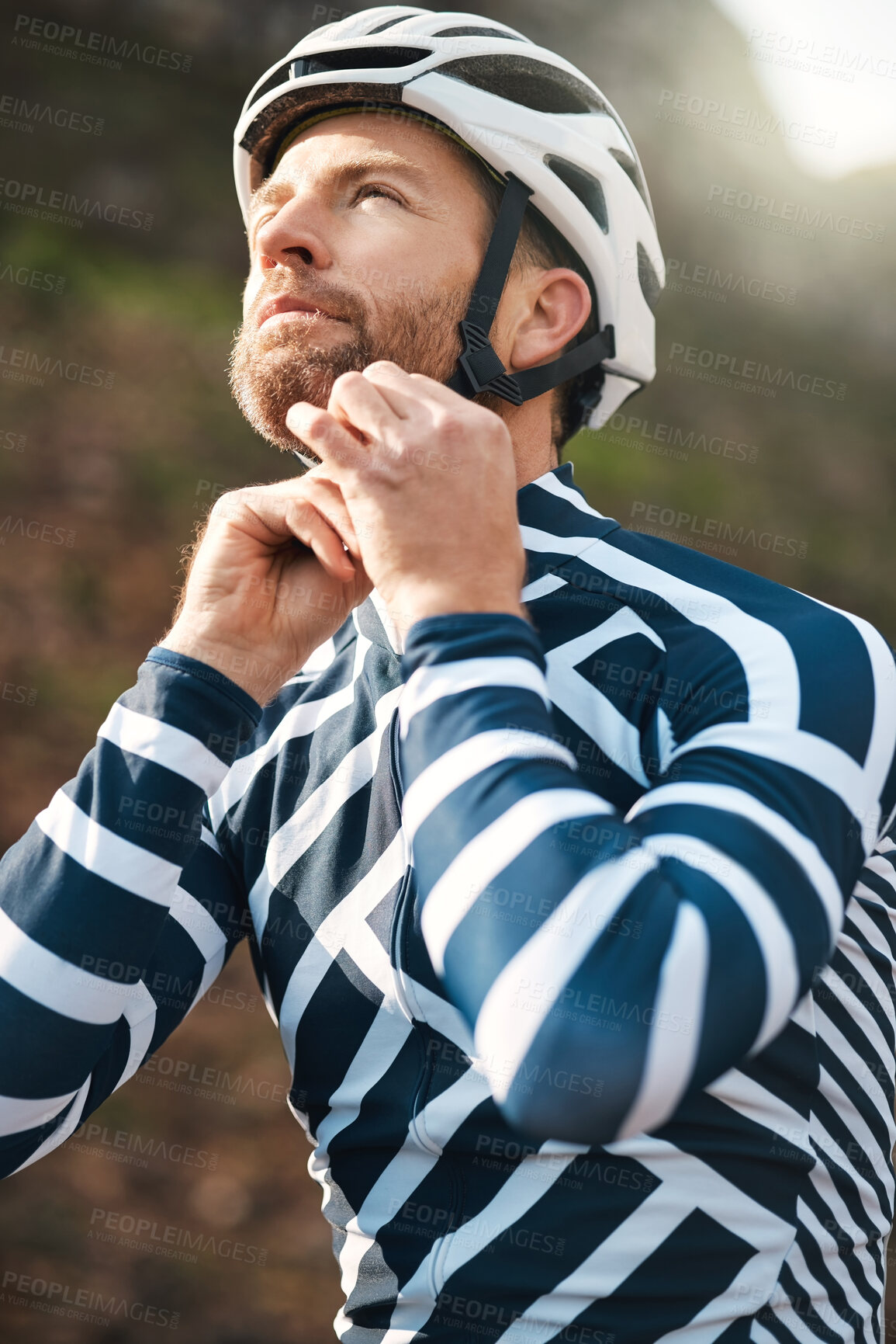 Buy stock photo Cropped shot of a handsome mature man fastening his helmet while cycling outdoors