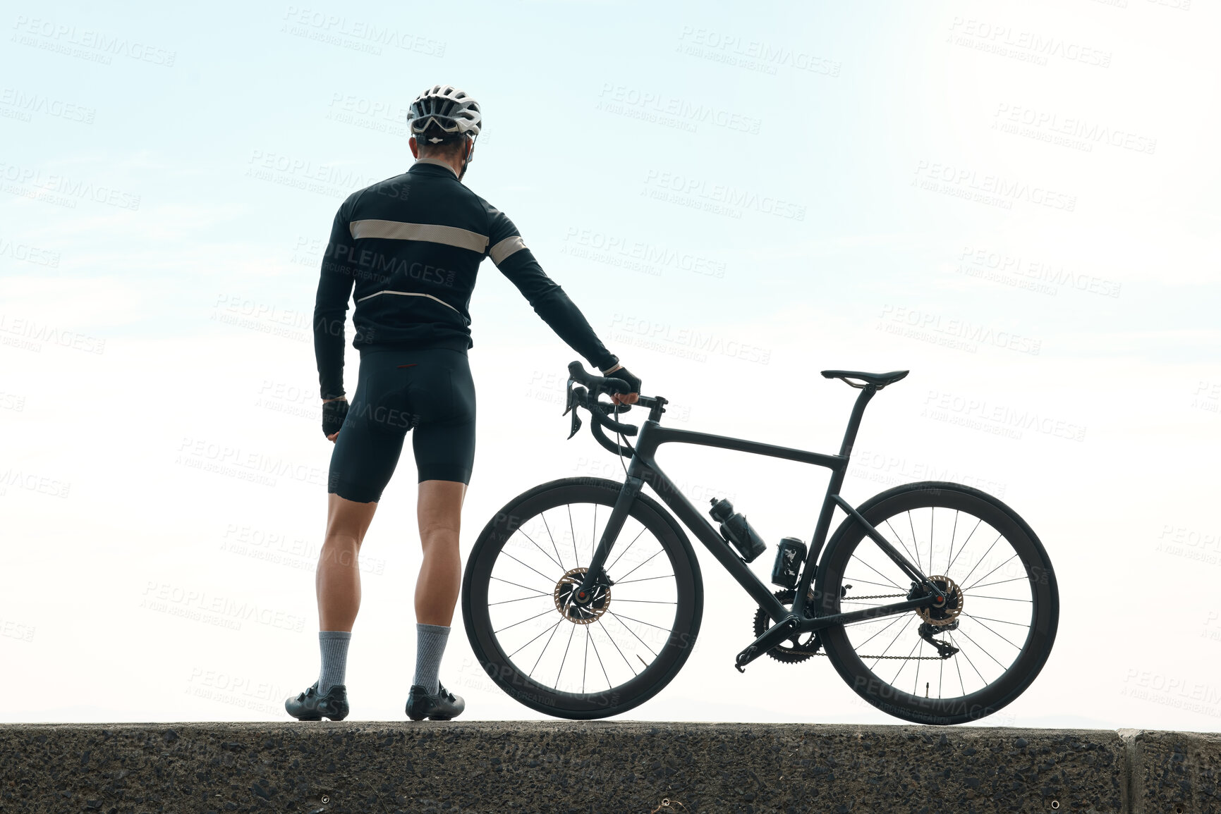 Buy stock photo Rearview shot of an unrecognizable man taking a break to admire the view while cycling outdoors