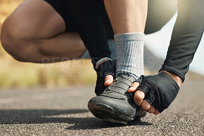 Buy stock photo Cropped shot of an unrecognizable man tying his laces while cycling outdoors