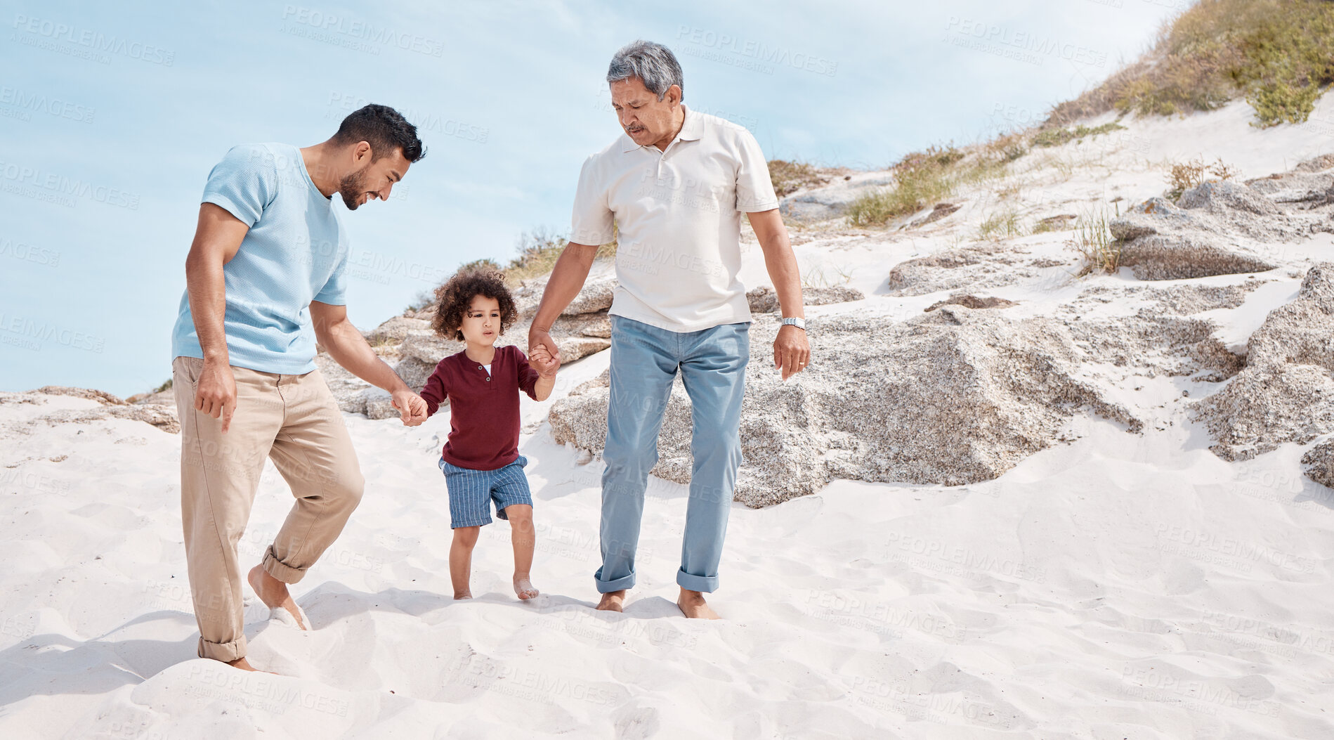 Buy stock photo Shot of a little boy at the beach with his father and grandfather