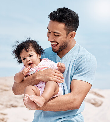 Buy stock photo Shot of a man holding his baby while standing on the beach