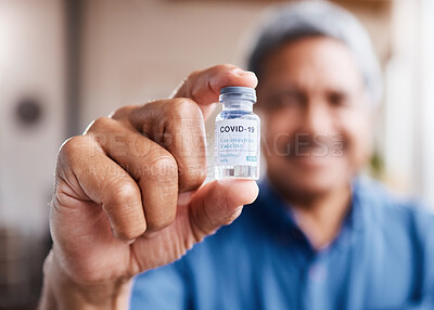 Buy stock photo Shot of an elderly man holding the Covid19 vaccine in his hand while relaxing at home