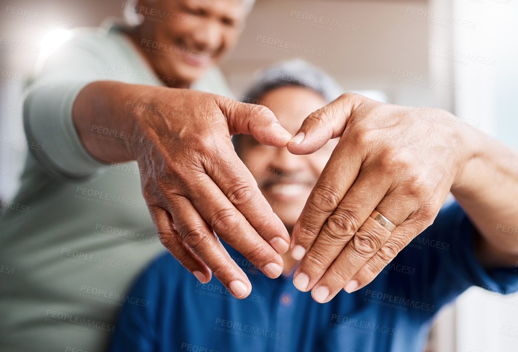 Buy stock photo Shot of a happy senior couple forming a heart shape with their fingers while  relaxing together at home