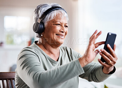 Buy stock photo Shot of a beautiful senior woman listening to music while sitting on the sofa at home
