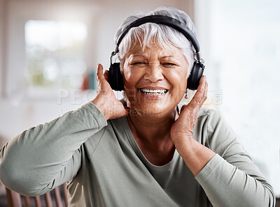 Buy stock photo Shot of a beautiful senior woman listening to music while sitting on the sofa at home
