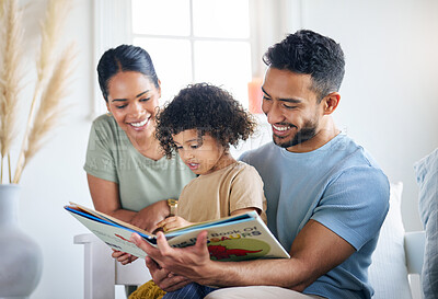 Buy stock photo Shot of a young family reading a book together at home