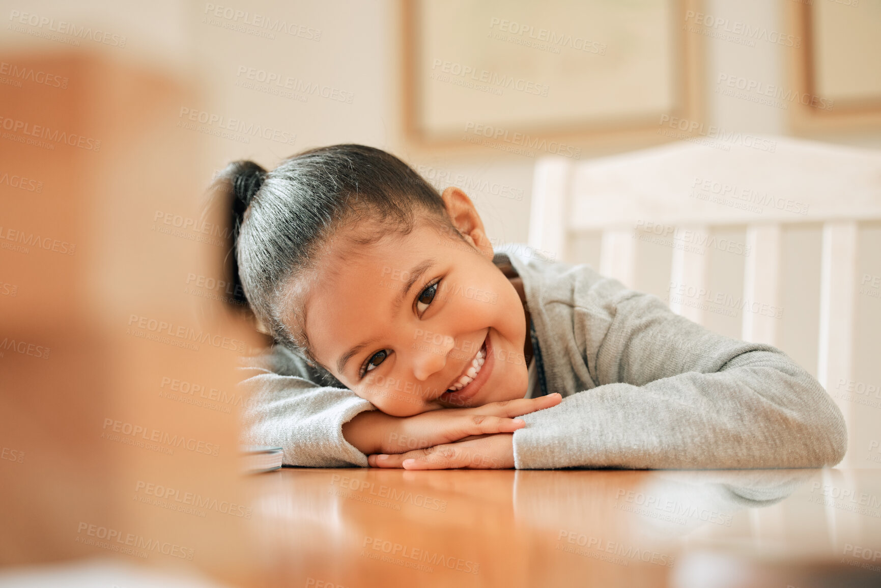 Buy stock photo Girl, child and relax by table with portrait in home on weekend break, cute and shy with adorable face. Female kid, smile and head on counter in house for playful, carefree and childhood fun or joy.