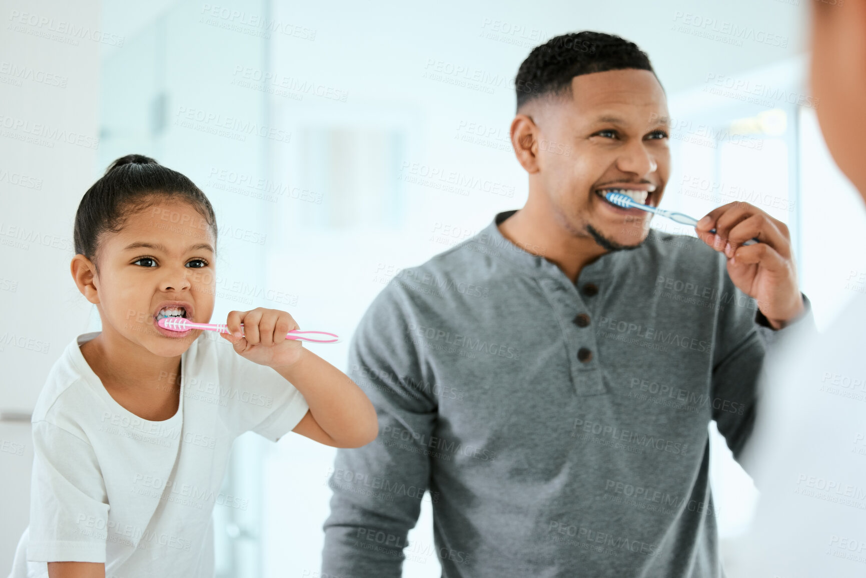 Buy stock photo Shot of an adorable little girl and her father brushing their teeth together at home