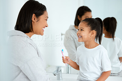 Buy stock photo Shot of an adorable little girl  brushing her teeth while her mother helps her at home
