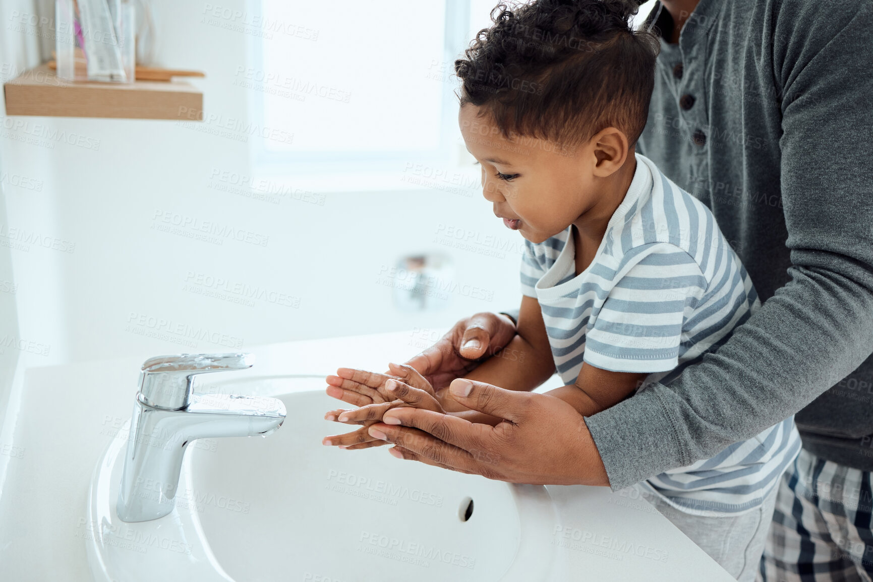 Buy stock photo Shot of an adorable little boy washing his hands with the help of his father at home
