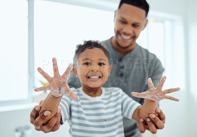 Buy stock photo Shot of an adorable little boy washing his hands with the help of his father at home