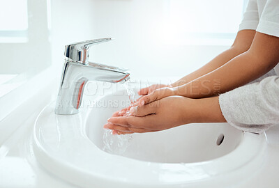 Buy stock photo Shot of an unrecognizable little girl washing her hands while her mother helps at home