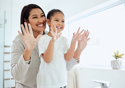 Buy stock photo Shot of an adorable little girl washing her hands while her mother helps at home