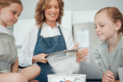 Buy stock photo Closeup shot of a grandmother sifting flour while baking with her two granddaughters at home