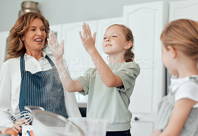 Buy stock photo Shot of a little girl playing with flour while baking with her sister and grandmother at home